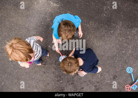 Auf drei Jungs spielen im Freien mit Blasen Stockfoto