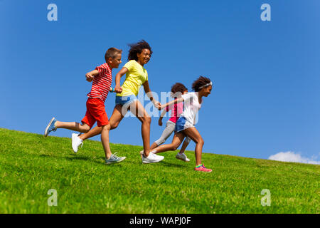Vier Glückliche diverse suchen Kinder laufen auf Rasen Stockfoto