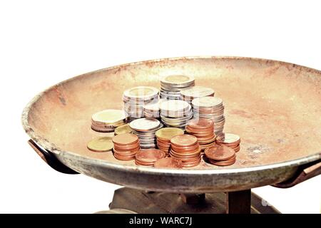 Viele Stapel von Münzen in verschiedenen Größen und auf vintage Küchenwaage auf weißem Hintergrund bewertet, finanzielle und wirtschaftliche Konzept verpflichten Stockfoto