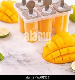 Frische mango Obst popsicle Eis in die plastische Gestaltung der Box auf hellem Marmor tisch. Sommer Stimmung Konzept Produkt Design, bis zu schließen. Stockfoto