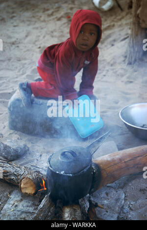 Junge helfen einen Topf Nshima, einem dicken Brei aus fein gemahlenen Maismehl, Mwandi, Sambia, Afrika zu kochen. Stockfoto