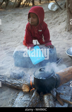 Junge helfen einen Topf Nshima, einem dicken Brei aus fein gemahlenen Maismehl, Mwandi, Sambia, Afrika zu kochen. Stockfoto