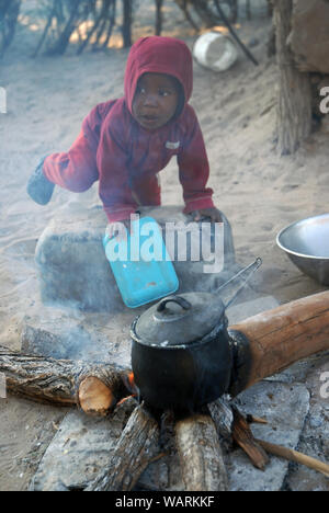 Junge helfen einen Topf Nshima, einem dicken Brei aus fein gemahlenen Maismehl, Mwandi, Sambia, Afrika zu kochen. Stockfoto