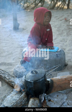 Junge helfen einen Topf Nshima, einem dicken Brei aus fein gemahlenen Maismehl, Mwandi, Sambia, Afrika zu kochen. Stockfoto