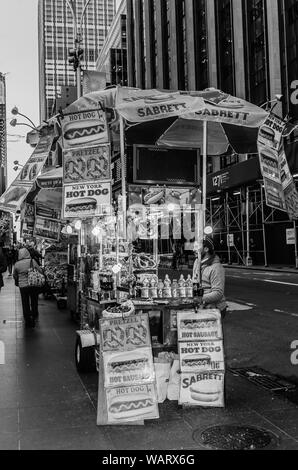 Straßenhändler in New York City Verkauf von Würstchen und Brezeln aus seinem Street Food Warenkorb. Stockfoto