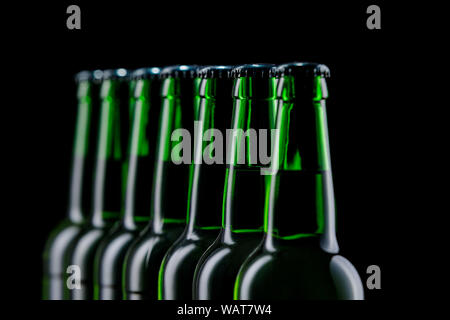 Zeile aus Glas Flaschen Bier auf dunklem Hintergrund Stockfoto