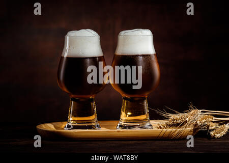 Zwei Gläser kalte dunkle Bier und Weizen ährchen auf dunklem Hintergrund. Stockfoto