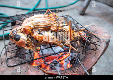 Köstliche gegrillte Garnelen auf flammende Grill. Garnelen kochen Meeresfrüchte auf Ofen verbrannt. Stockfoto