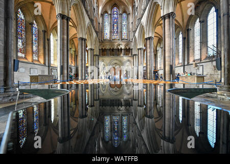 Touristen und Besucher versammeln unter der west Fenster in der Schriftart während die Kathedrale von Salisbury Turm Tour, wo die Besucher auf der Basis der 123 Meter hohe Turm geführt werden reflektiert werden, Klettern 332 hauptsächlich Spirale Schritte, durch die gewölbten Dach Platz, vorbei an mittelalterlichen Glasmalereien und über das Innenleben der Kathedrale aus dem 13. Jahrhundert. Stockfoto