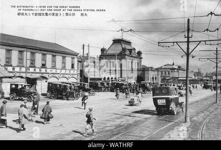 [1920s Japan - Taxis in Osaka Station] - Die zweite Osaka Station in Umeda, Osaka City. Im Juli 1901 (Meiji 34) geöffnet, das Gotische Gebäude wurde zwei Stockwerke hoch und aus Granit gebaut, so dass es eine massive und imposant Aussehen. Es wurde eine von der Stadt drei müssen - siehe touristische Attraktionen. Die große weiße Zeichen über die Autos, sagt Osaka Takushi Jidosha KK, die Osaka Zweig von Japans erste Taxi unternehmen. 20. jahrhundert alte Ansichtskarte. Stockfoto