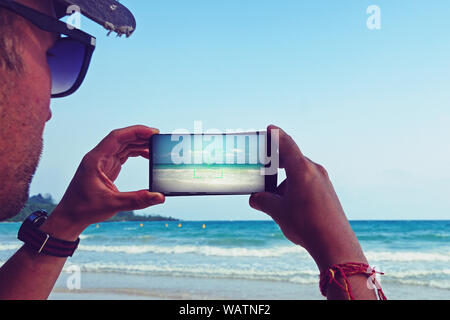 Mann Bild Meer Blick auf Telefon. Foto der schönen Meer mit klarem, türkisfarbenem Wasser und blauer Himmel. Schönen exotischen Insel im Indischen Ozean. Ein Stockfoto