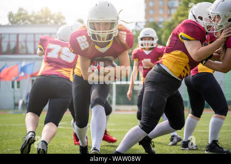 In voller Länge Bild des Athleten Frauen spielen American Football auf grünem Rasen auf Sommertag. Lensflare Effekt. Stockfoto