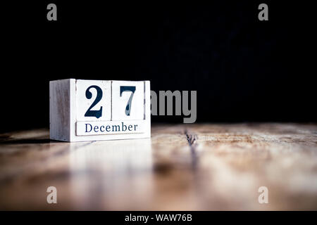 27. Dezember 27. Dezember, 20 7. Dezember - weißer Block Kalender auf vintage Tabelle - Datum auf dunklem Hintergrund Stockfoto