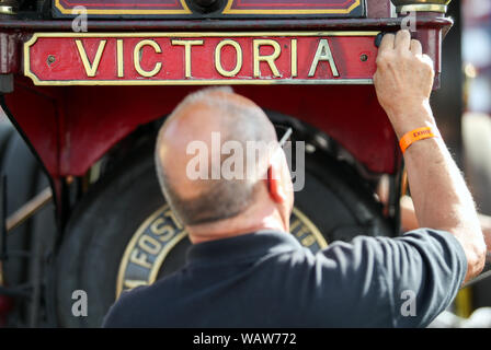 Eine Person poliert die Namen Plakette auf der fördert Showman Motor 'Victoria' während des Tages eine der großen Dorset Steam Fair, wo Hunderte von Zeitraum dampfbetriebene Zugmaschinen und schwere mechanische Ausrüstung aus allen Epochen zu präsentieren Großbritanniens reiche industrielle, landwirtschaftliche und Freizeit Geschichte sammeln, bei der jährlichen zeigen, statt über den August Bank Holiday Wochenende von Donnerstag 22. bis Montag, den 26. August. Stockfoto