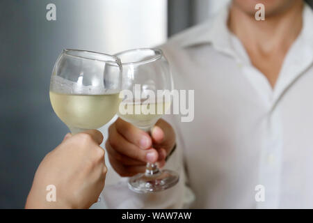 Paar trinken Weißwein auf ein romantisches Date. Frau und Mann im weißen Hemd clink von Beschlagenen Weingläser, Konzept der Hochzeit, Feier, liebe Datum Stockfoto