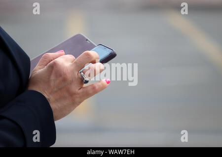 Frau mit Smartphone auf einer Straße. In der Nähe der weiblichen Händen mit Handy, sms, online sucht, soziale Medien Stockfoto