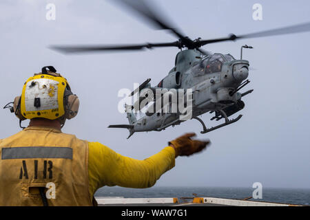 190815-N-NB 544-1030 Golf von Aden (Aug. 15, 2019) der Luftfahrt Bootsmann Mate (Handling) 3. Klasse James Ling, Signale zu AH-1Z Viper Piloten, zu Marine Medium Tiltrotor Squadron (VMM) 163 (Verstärkt) zugewiesen, während der flugbetrieb an Bord des amphibious Transport dock Schiff USS John Murtha (LPD S. 26). John Murtha Teil der Boxer Amphibious Ready Gruppe und 11 Marine Expeditionary Unit und ist in die USA 5 Flotte Bereich der Maßnahmen zur Unterstützung der Marine im Einsatz für die Stabilität und Sicherheit in der Region zu gewährleisten und verbindet das Mittelmeer und den Pazifischen durch Stockfoto