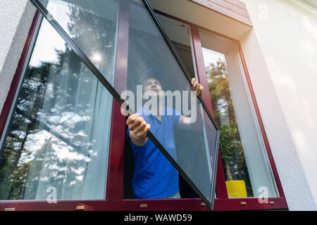 Arbeitnehmer installation Moskitonetz Drahtgitter auf Kunststoff PVC-Fenster Stockfoto