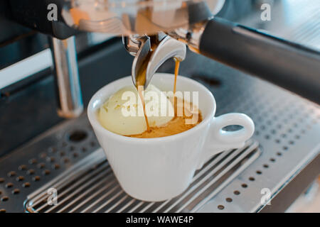 Affogato Kaffee mit Eis auf einem keramischen Tasse mit Kaffee Gießen von Espresso Maschine Stockfoto
