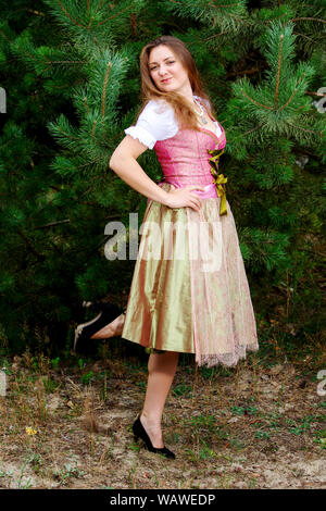 Porträt der jungen Frau im Dirndl durch Baum stehend Stockfoto