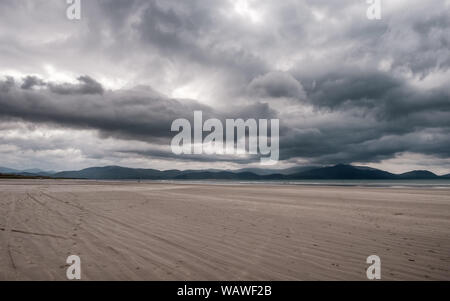 Dunkle Wolken über der großen Sandstrand und die fernen Hügel von Zoll Strand auf der Halbinsel Dingle im Südwesten Irlands Stockfoto