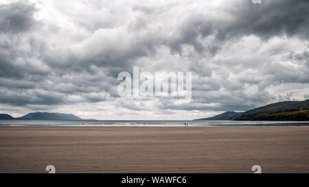 Dunkle Wolken über der großen Sandstrand und die fernen Hügel von Zoll Strand auf der Halbinsel Dingle im Südwesten Irlands Stockfoto