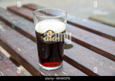 Teil voll pint Glas Theakston's Old Peculier Ale Bier vom Fass auf den Tisch, Großbritannien Stockfoto