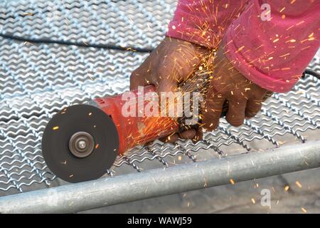 Man Winkelschleifer ohne Schutzabdeckung Schneiden von Metall net Vogelkäfig zu machen. Stockfoto