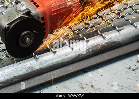 Man Winkelschleifer ohne Schutzabdeckung Schneiden von Metall net Vogelkäfig zu machen. Stockfoto