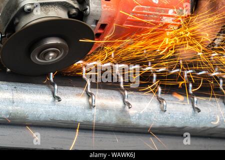 Man Winkelschleifer ohne Schutzabdeckung Schneiden von Metall net Vogelkäfig zu machen. Stockfoto