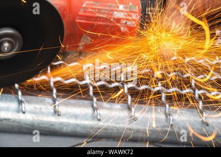 Man Winkelschleifer ohne Schutzabdeckung Schneiden von Metall net Vogelkäfig zu machen. Stockfoto