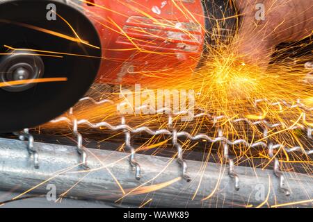 Man Winkelschleifer ohne Schutzabdeckung Schneiden von Metall net Vogelkäfig zu machen. Stockfoto