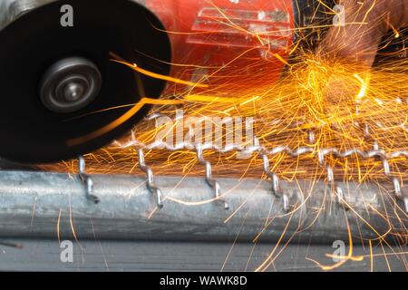 Man Winkelschleifer ohne Schutzabdeckung Schneiden von Metall net Vogelkäfig zu machen. Stockfoto