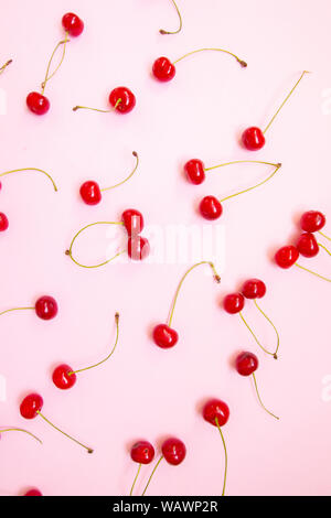 Kreative Gestaltung aus Flach der Kirschen auf einem rosa Hintergrund. Minimalismus, Flach, Ansicht von oben, Design. Stockfoto