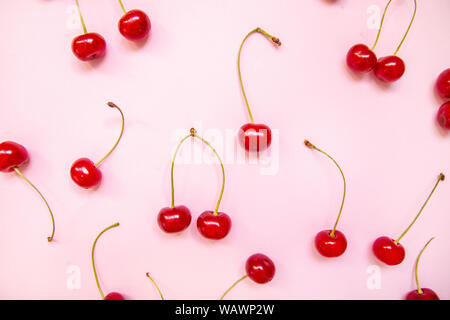 Kreative Gestaltung aus Flach der Kirschen auf einem rosa Hintergrund. Top View Stockfoto