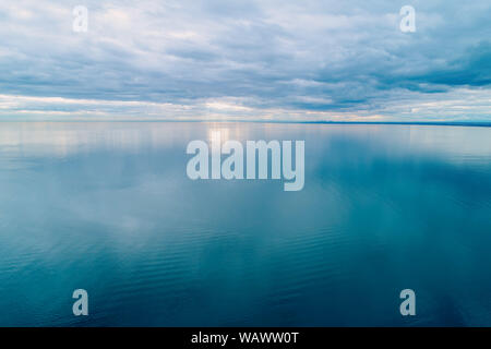 Minimalistische Antenne Seascape. Bewölkten Himmel über ruhige und glatte Wasseroberfläche Stockfoto