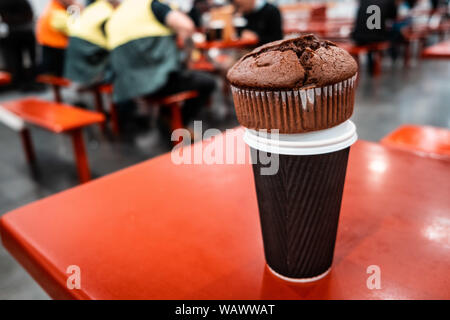Schokolade Kuchen auf der hohen Kaffeetasse auf food court Rote Tabelle mit unscharfen Menschen in den Hintergrund gestellt Stockfoto
