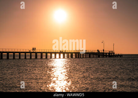 Menschen Silhouetten genießen Sie den Sonnenuntergang über dem Meer auf einem hölzernen Pier Stockfoto