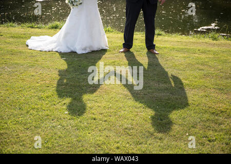 Schatten auf der Basis einer Braut und Bräutigam, Hände halten am Tag ihrer Hochzeit, Schatten einer Braut und Bräutigam, an einem sonnigen Tag der Hochzeit in England Stockfoto