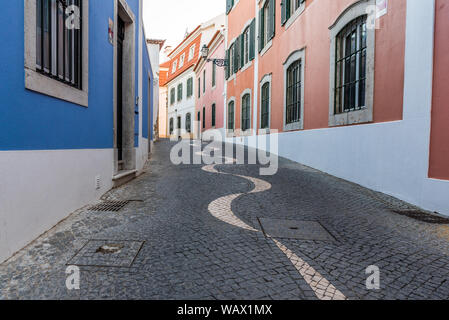 Verwinkelten engen, kopfsteingepflasterten Gasse in Portugiesisch Pflaster calçada Muster entfernt zwischen traditionellen weißen und bunten Häusern aus Stein Stockfoto