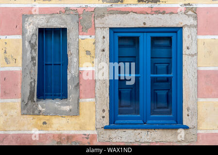 Blauen Fensterrahmen und Rollläden vor kurzem in bunten stein Wand von heruntergekommenen Straße Haus in der Altstadt von Cascais Portugal lackiert eingestellt Stockfoto