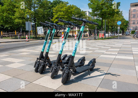 Vier Stufe elektrische Kick-Roller auf dem Bürgersteig in München geparkt. Stockfoto