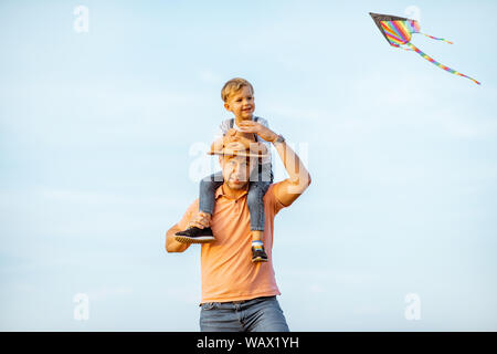 Portrait eines glücklichen Vater mit Sohn, auf den Schultern auf den blauen Himmel Hintergrund im Freien. Konzept einer glücklichen Familie auf einem Sommer Aktivitäten Stockfoto