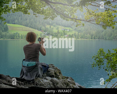 Junge Frau nimmt Fotos von wunderschönen See, in den Bergen Stockfoto