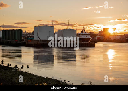 Öltanks auf einem Pier in einem kommerziellen Hafen bei Sonnenuntergang Stockfoto