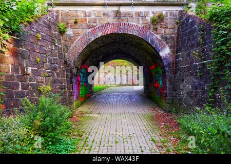 Dunklen Tunnel mit viel Graffiti unter einem verlassenen Bahnhof Anschluss Stockfoto