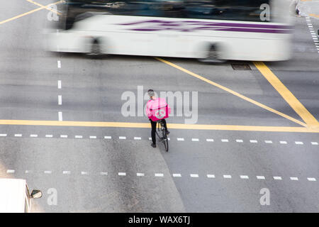 Food Panda Lieferservice Mann mit Kappe, mit seinem Fahrrad auf der Straße, während auf den geschäftigen Verkehr an der Kreuzung warten. Stockfoto