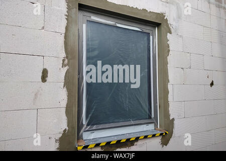 Fenster von einem Haus im Bau mit Schutzfolie abgedeckt. Stockfoto