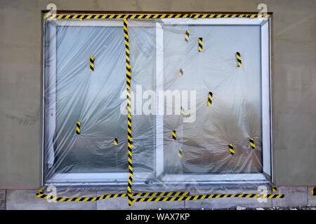 Fenster von einem Haus im Bau mit Schutzfolie abgedeckt. Stockfoto