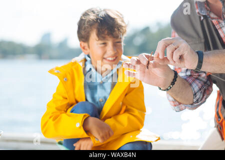 Junge lächelnd, während Opa putting Wurm auf Angeln Haken Stockfoto